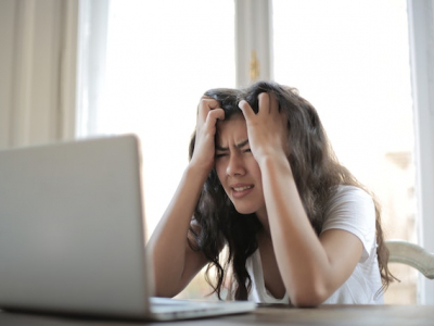 A woman sitting at a laptop looking exasperated.